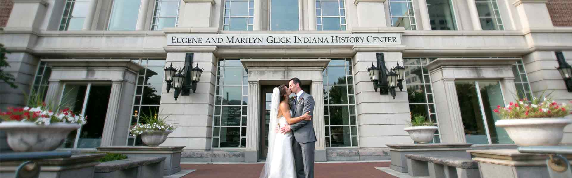 Bride and Groom kissing in front of History Center building.